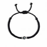 Black braided bracelet with a small round bead on a white background