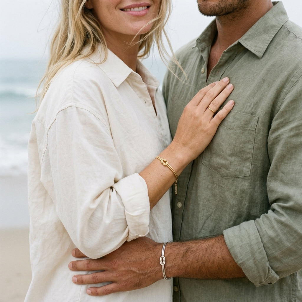 Couple embracing on the beach, wearing matching gold and silver Love Knot Bracelets