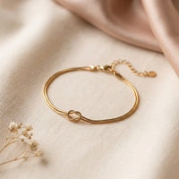Gold Love Knot Bracelet with lobster clasp and adjustable extender chain on cream linen