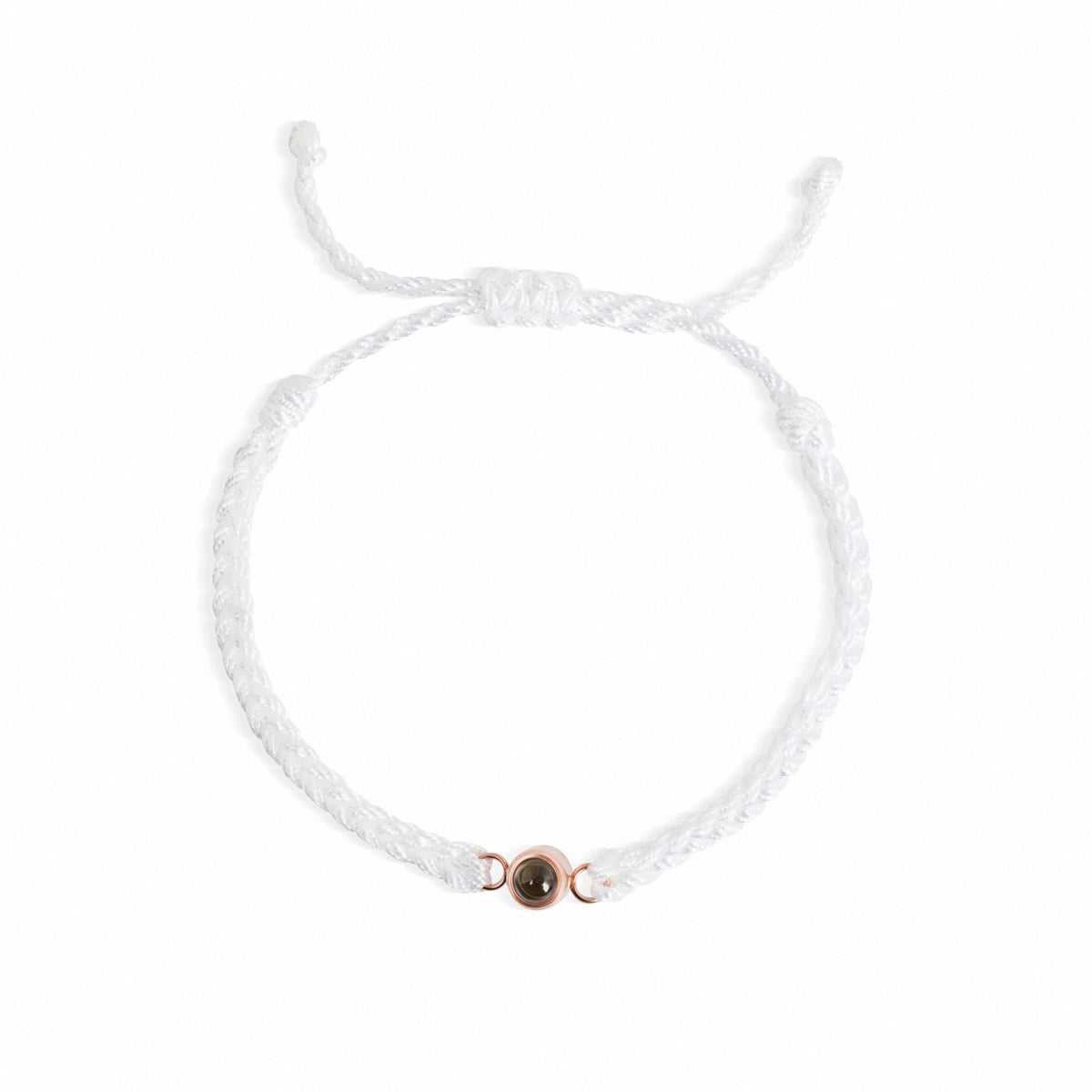 A delicate white braided cord bracelet with an adjustable sliding knot and a small rose gold circular charm featuring a dark center, shown on a plain white background.