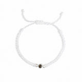 A delicate white braided cord bracelet with an adjustable sliding knot closure and a small central metallic charm, displayed on a clean white background.