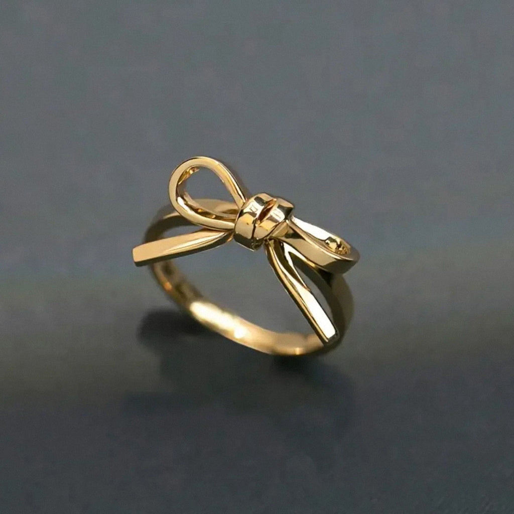 close up of shiny gold bow ring on dark surface