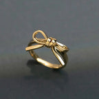 close up of shiny gold bow ring on dark surface