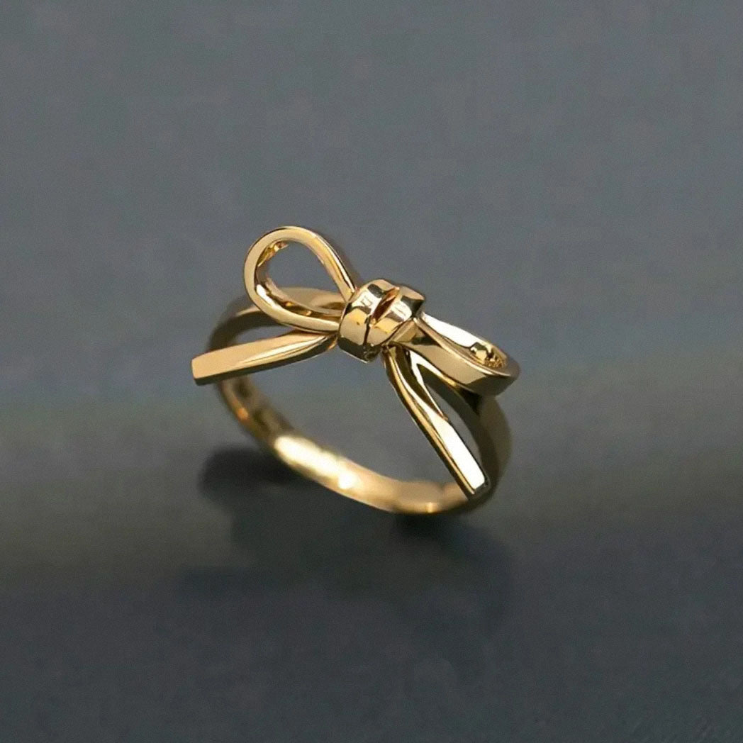 close up of shiny gold bow ring on dark surface