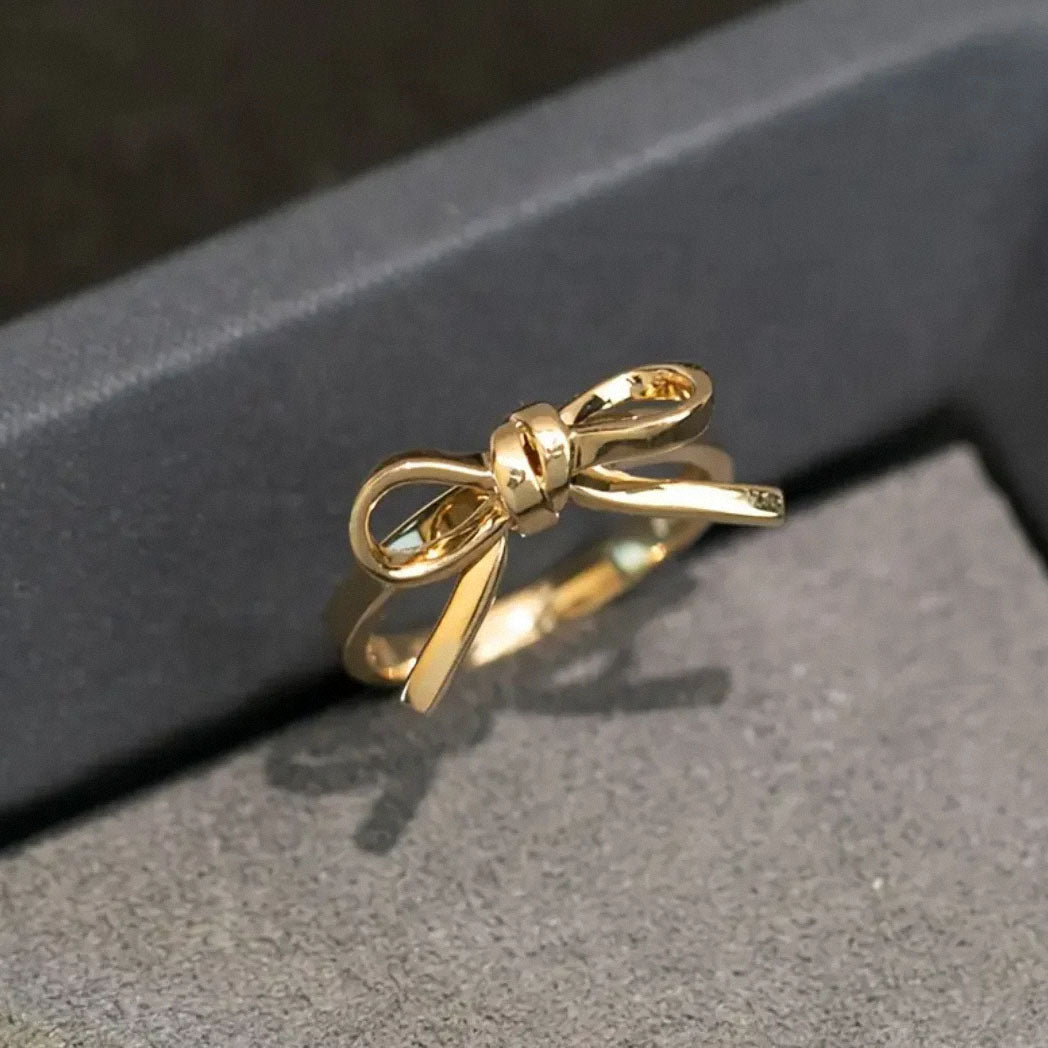 gold bow ring displayed in grey jewelry box