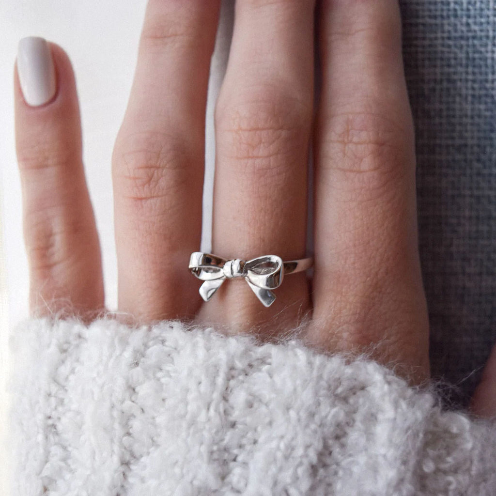 silver bow ring on hand with cozy white sweater