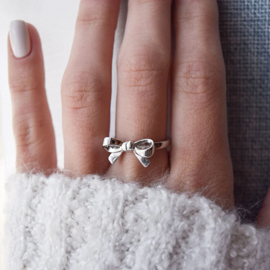 silver bow ring on hand with cozy white sweater
