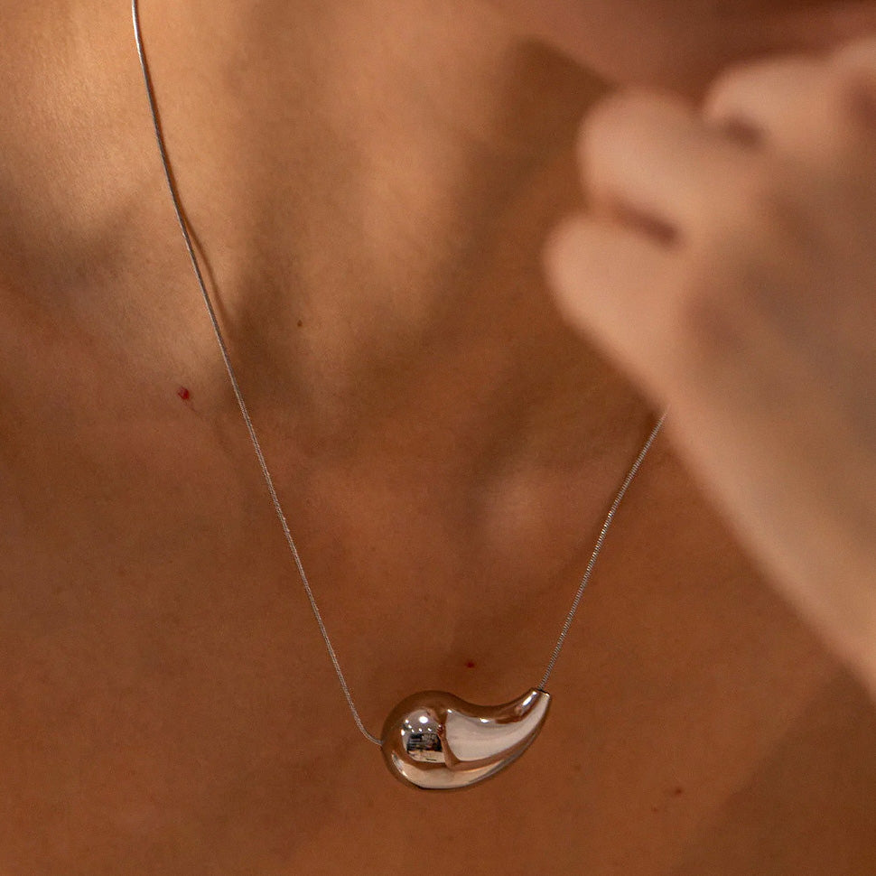 Minimal silver teardrop pendant necklace close-up on model
