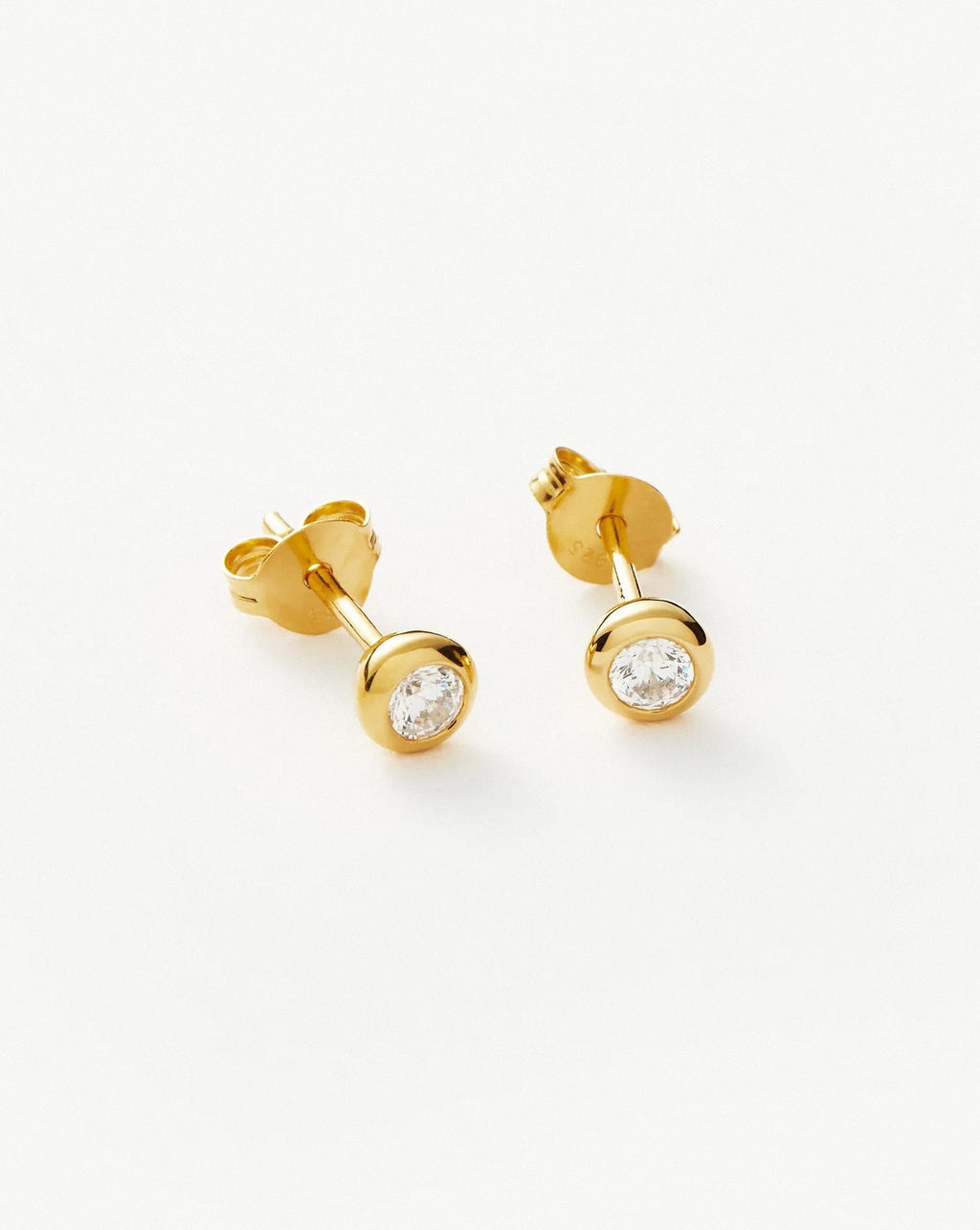 Minimalist gold bezel crystal stud earrings displayed on a white background