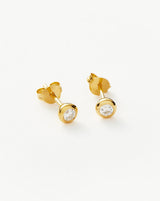 Minimalist gold bezel crystal stud earrings displayed on a white background