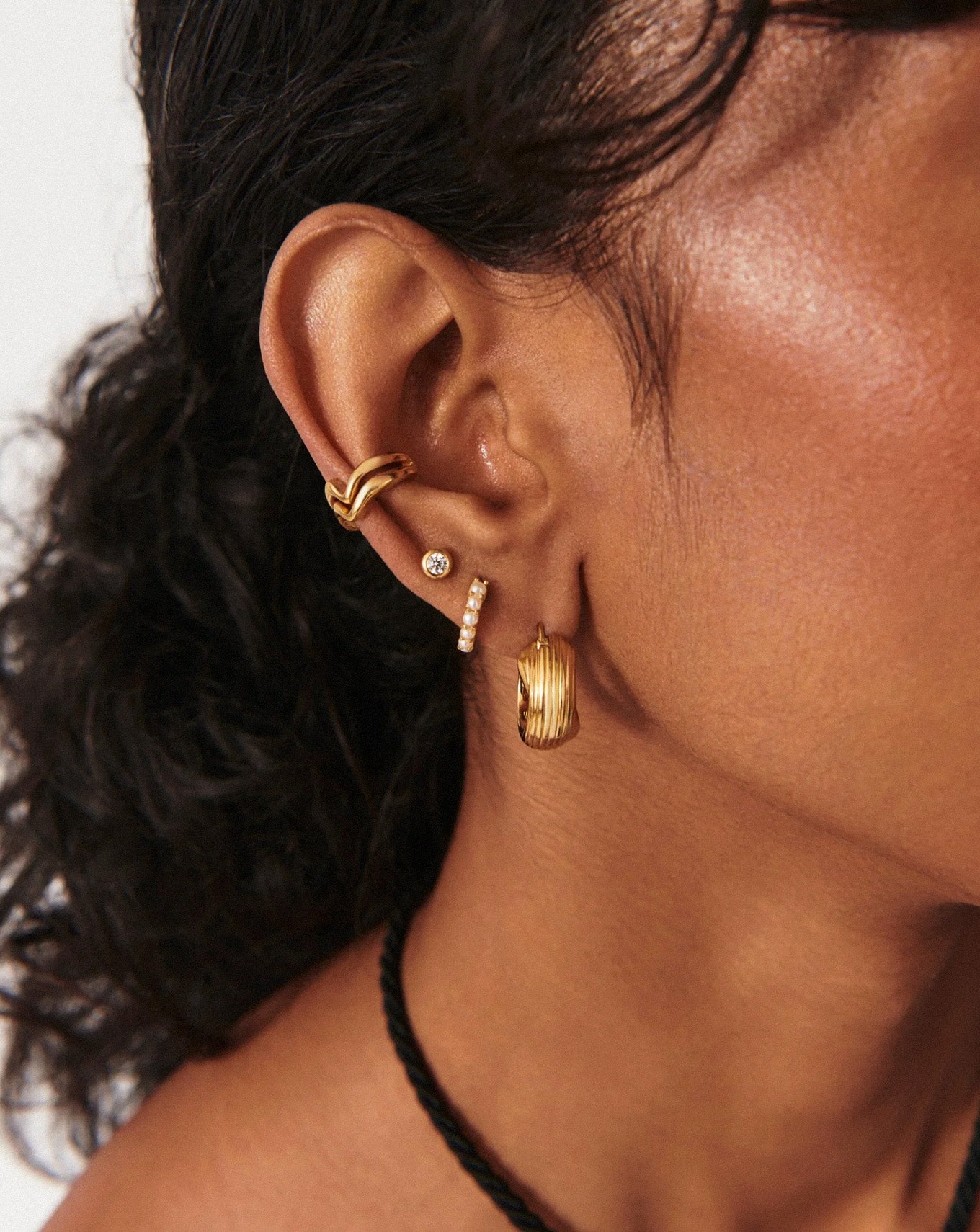 Lifestyle photo featuring gold bezel studs worn in a stacked ear look