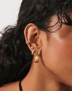 Model wearing small gold bezel crystal stud earrings with layered ear stack