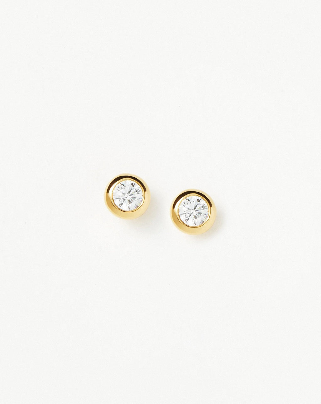 Detailed macro shot of gold bezel stud earrings showing crystal clarity