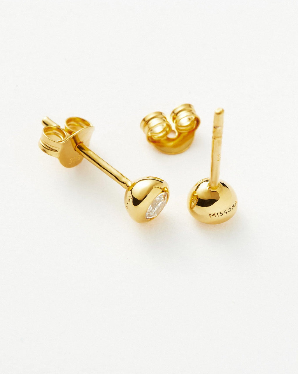 Close-up view of gold bezel stud earrings with round cubic zirconia stones