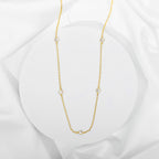 Gold station necklace with bezel-set cubic zirconia stones on white background