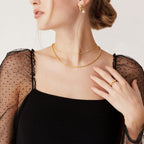 Delicate gold station necklace with cubic zirconia stones worn on model