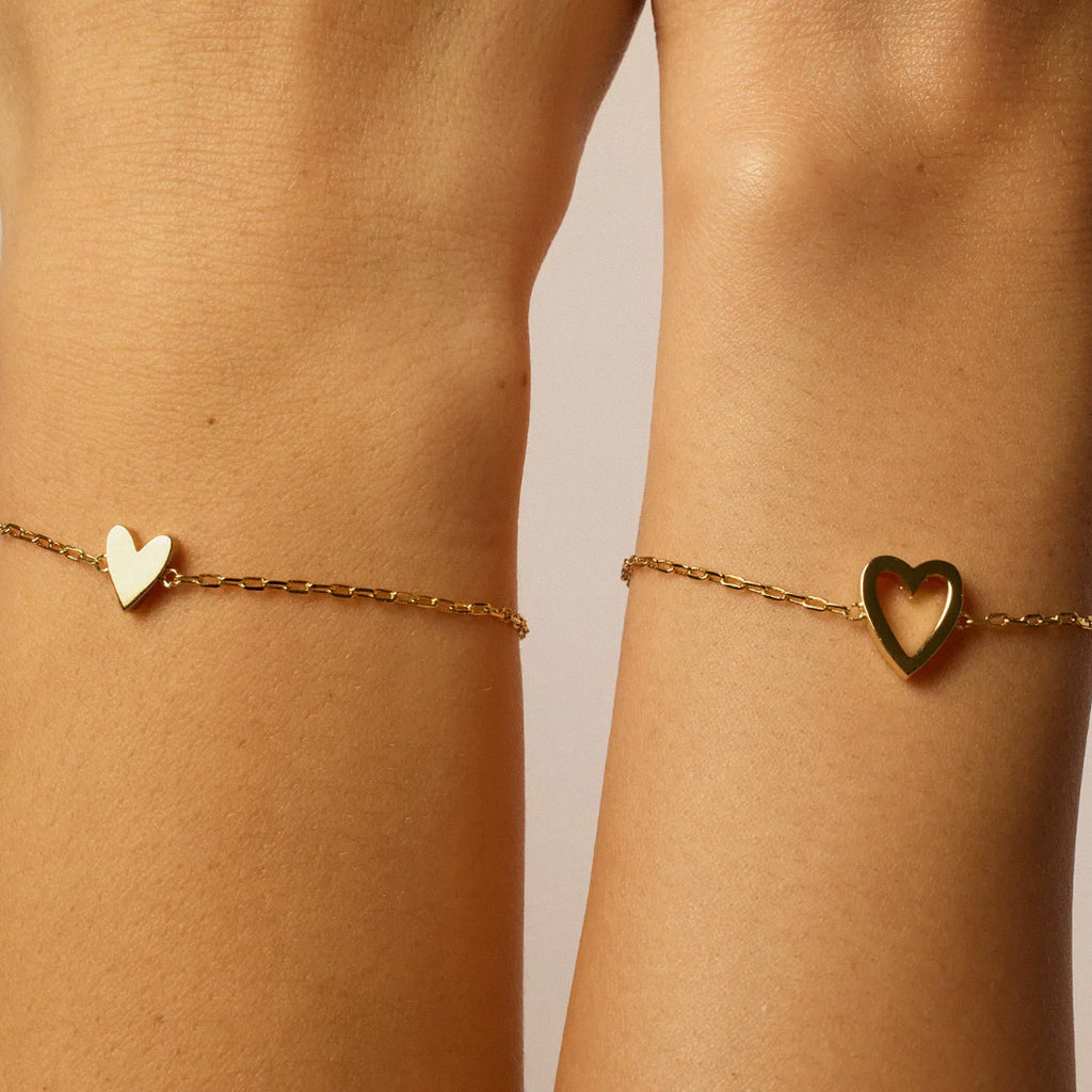 Close-up of gold heart bracelets worn as a matching duo