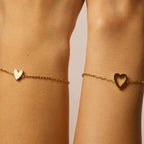Close-up of gold heart bracelets worn as a matching duo