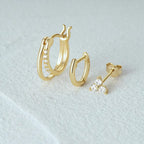 Gold hoop earrings and stud earrings on a light gray background