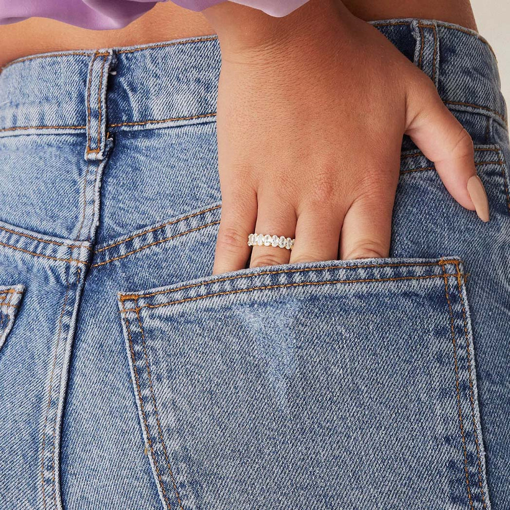 Lifestyle image of gold-plated oval zirconia eternity ring with hand in denim pocket