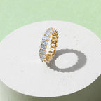 White gold-plated oval zirconia eternity ring displayed on minimal pedestal