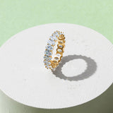 White gold-plated oval zirconia eternity ring displayed on minimal pedestal