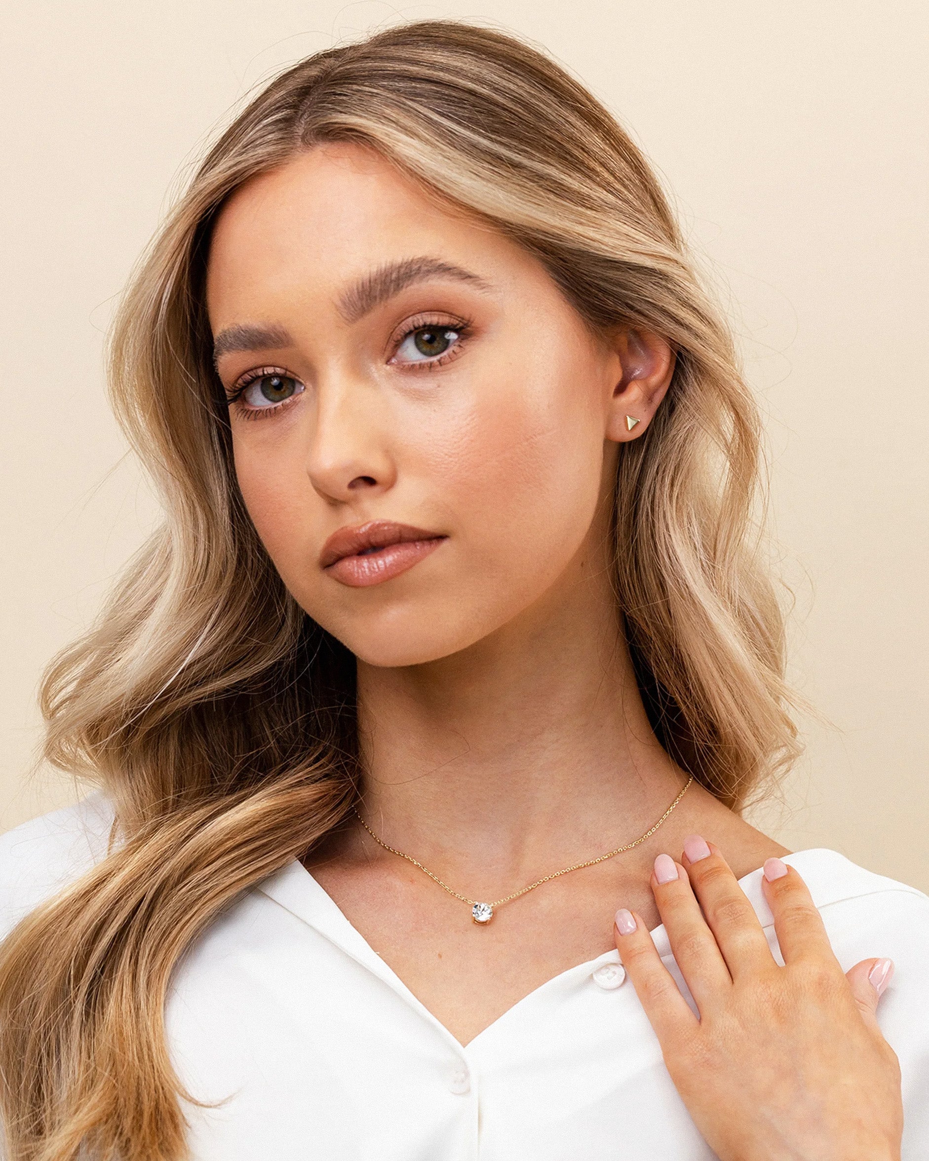 Woman wearing a delicate necklace with a plain background