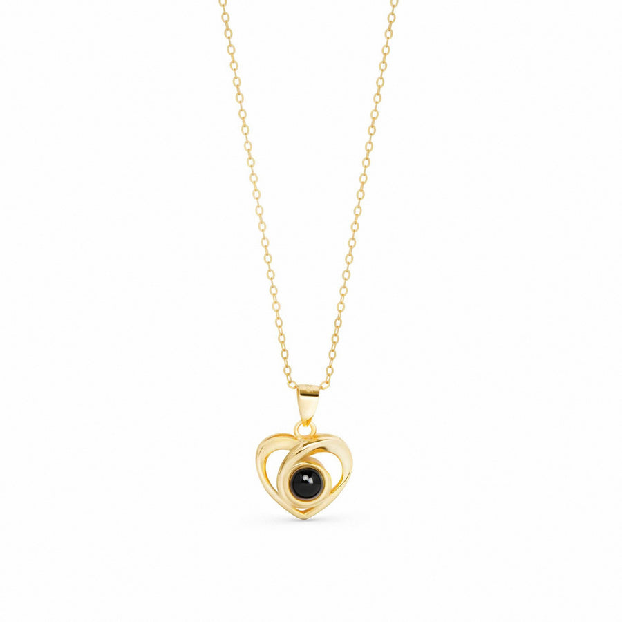 A gold pendant necklace featuring a double-heart design with a central black oval stone, suspended on a delicate gold chain against a plain white background.