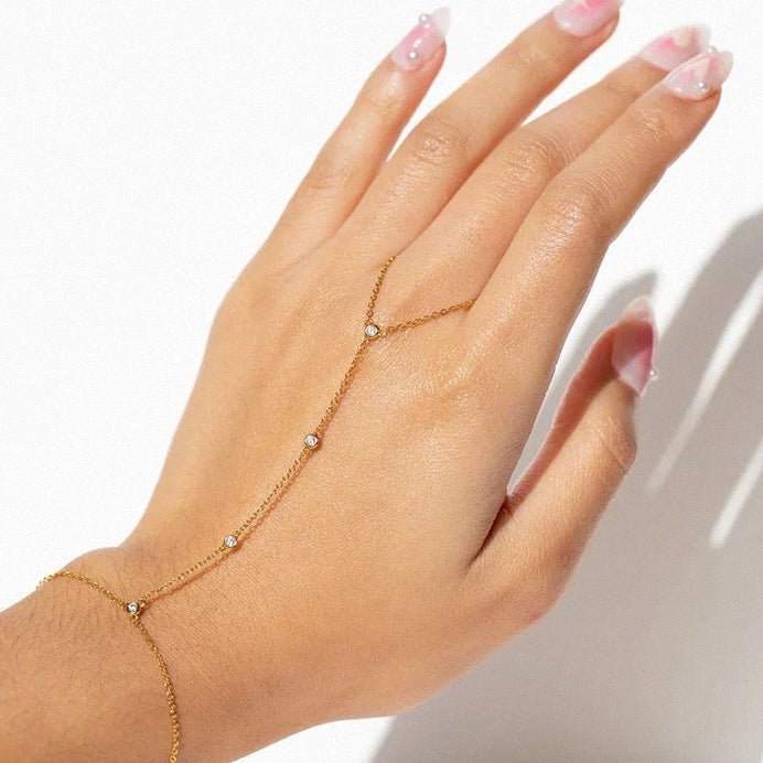 Layered jewellery look featuring gold crystal hand chain bracelet on wrist