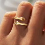 Gold hug ring with sculpted hand detail worn on finger