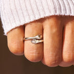 Silver hug ring with hand-shaped ends worn on finger