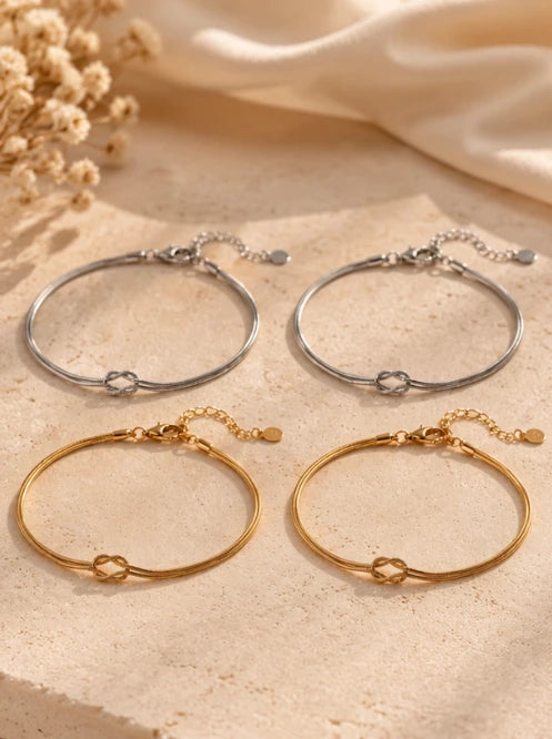 Two silver and two gold Love Knot Bracelets on travertine stone