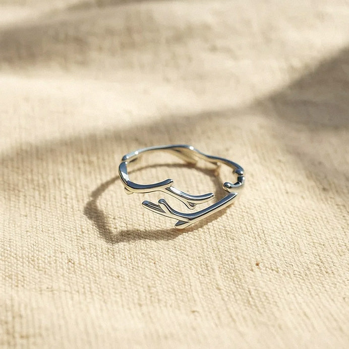 Minimalist silver branch ring displayed in natural light