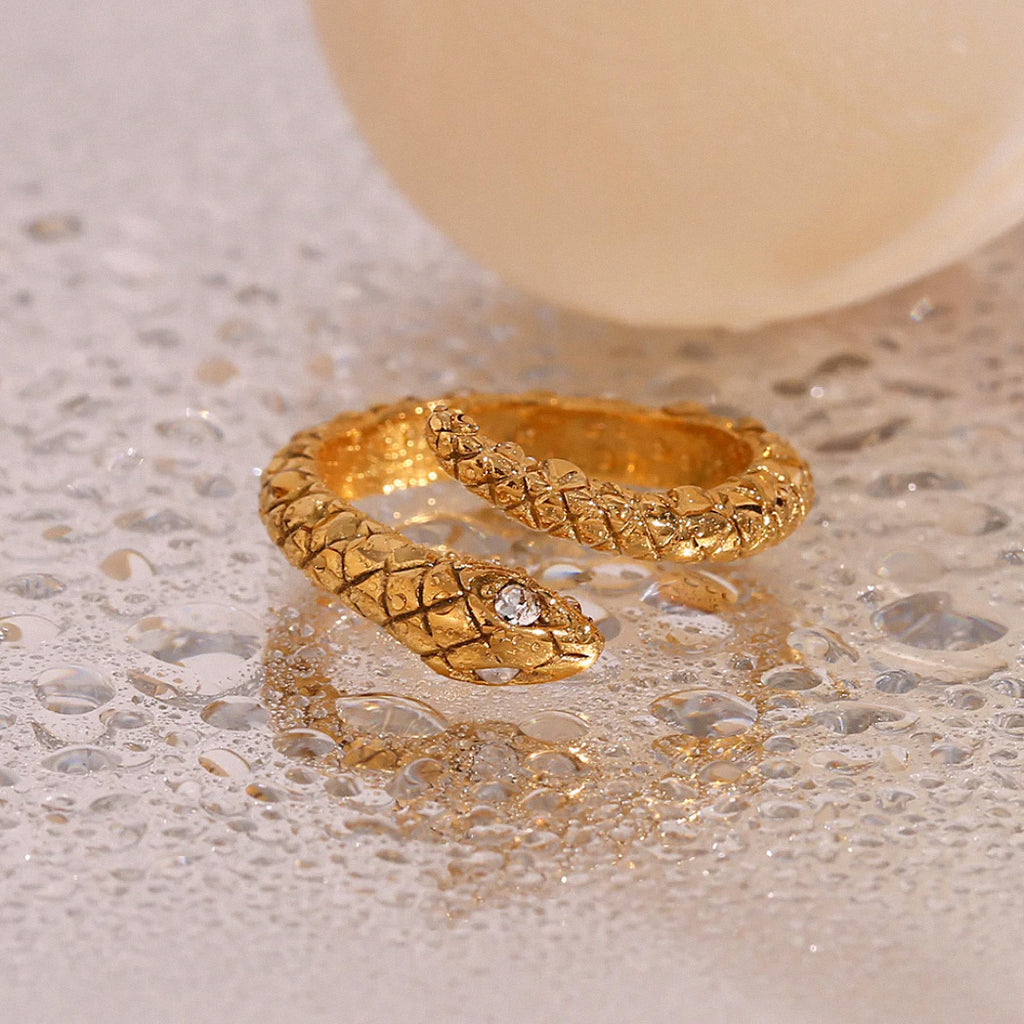 Gold snake ring with crystal detail shown on water-droplet background