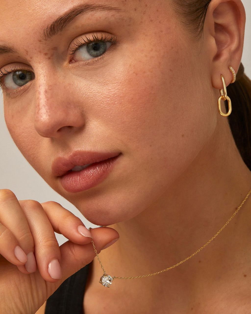 Model showcasing gold solitaire CZ pendant necklace close up.