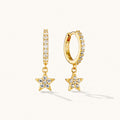 Gold star drop huggie earrings with crystal detailing on white background