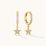 Gold star drop huggie earrings with crystal detailing on white background