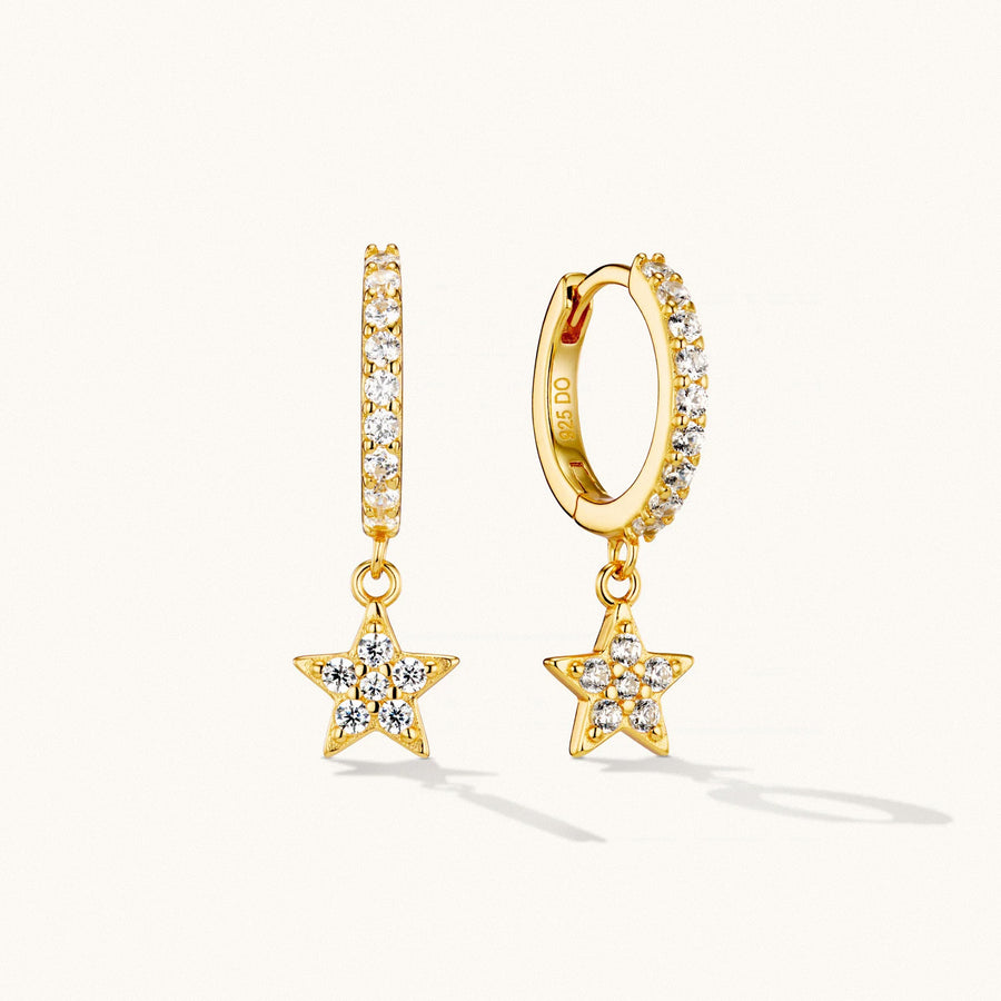 Gold star drop huggie earrings with crystal detailing on white background