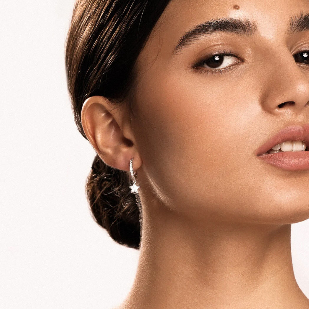 Minimalist gold huggie earrings with crystal star pendant on model