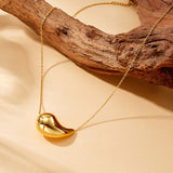 Gold teardrop necklace displayed on wood styling background