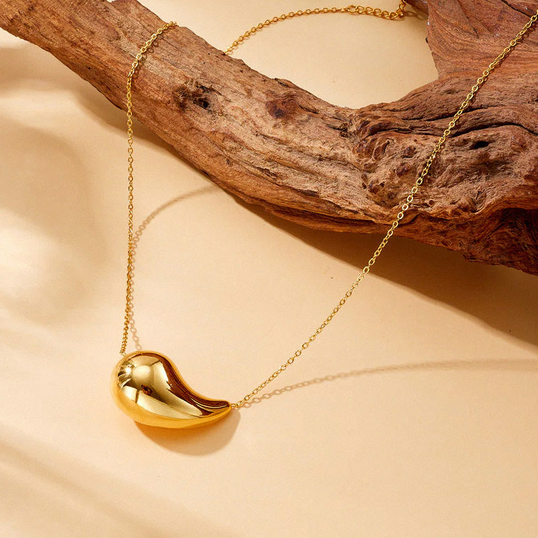 Gold teardrop necklace displayed on wood styling background