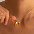Gold teardrop pendant necklace worn on model